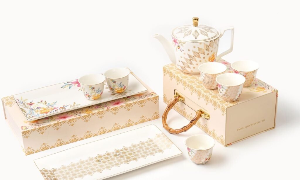 Casa Aseana teapot and small cups resting on their gift box, beside two Royal Songket Collection serving plates