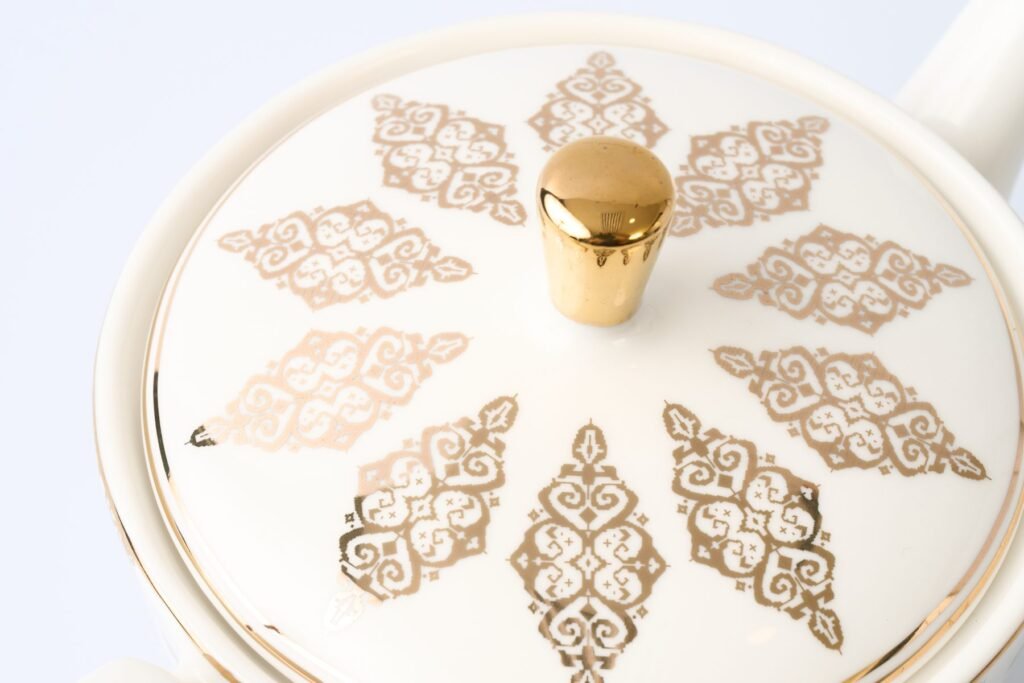 Close-up of the Casa Aseana teapot lid, gold songket motifs around a gold knob